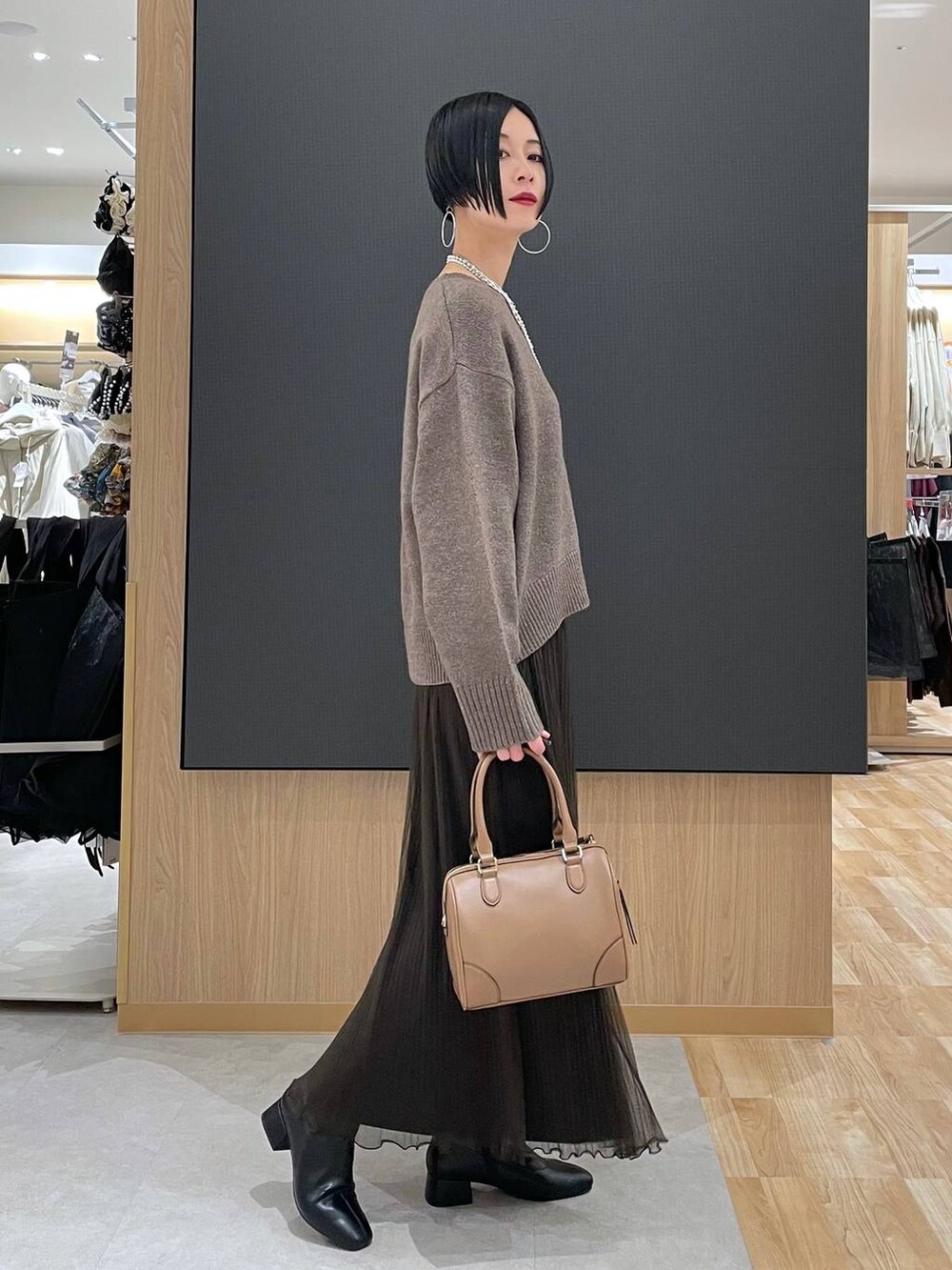 ベージュ系のボストンバッグ、ブラック系のブーツ、シルバー系のネックレスを着用したレディースの冬コーディネートの3枚目の写真