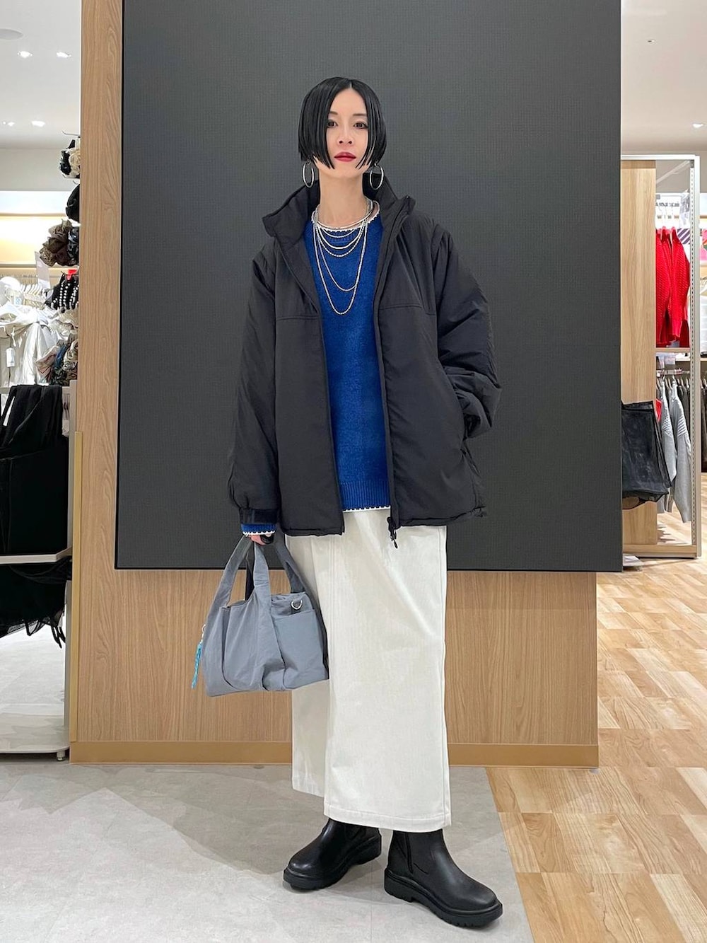 グレー系のトートバッグ、ブラック系のブルゾン、グレー系のスカートを着用したレディースの冬コーディネートの2枚目の写真