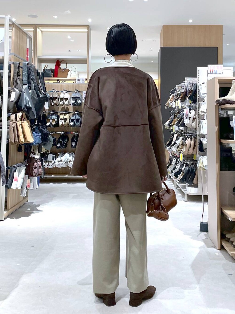 ブラウン系のハンドバッグ、ベージュ系のサロペット/オーバーオール、ホワイト系のニット/セーターを着用したレディースの秋コーディネートの3枚目の写真