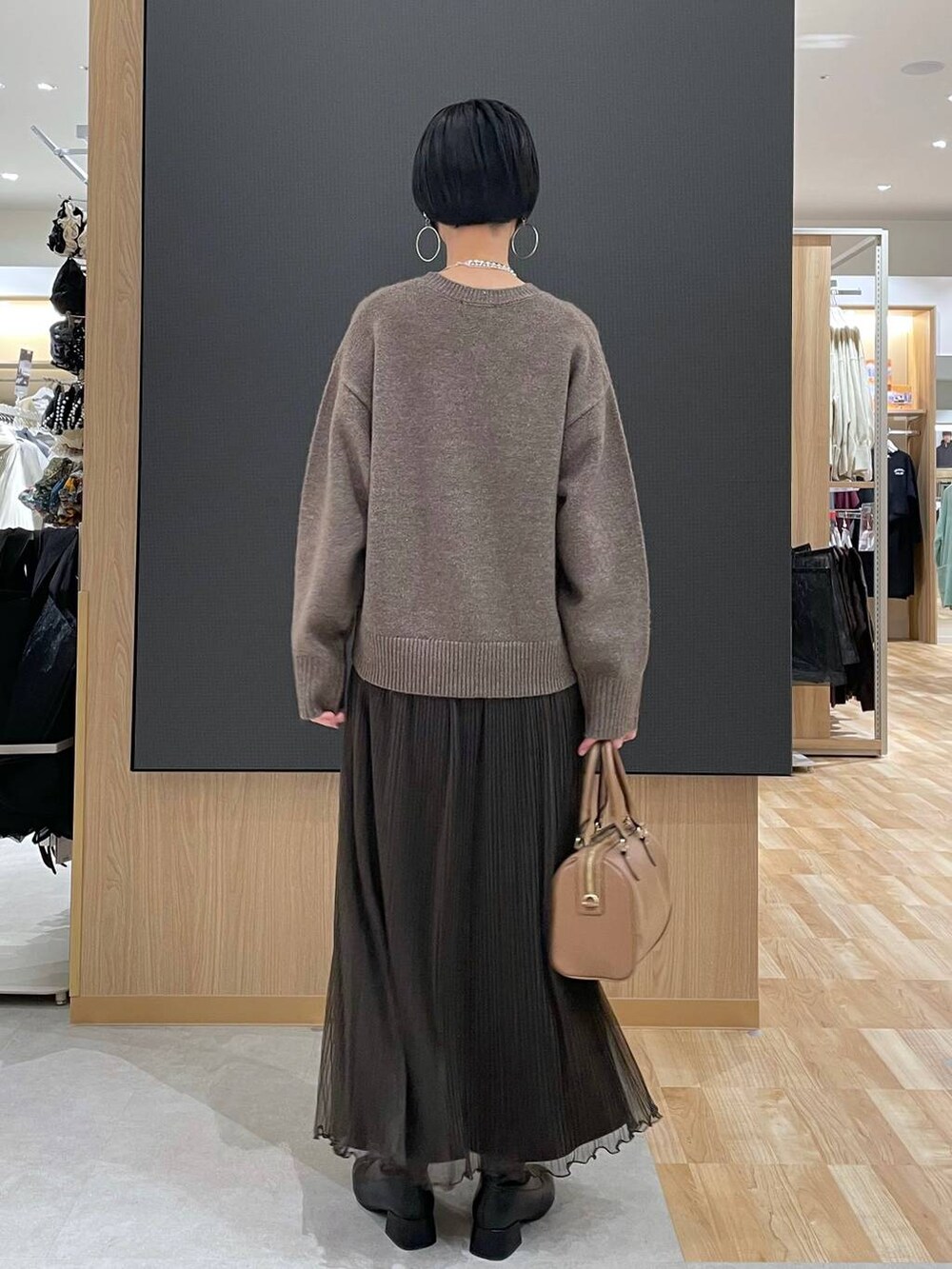 ベージュ系のボストンバッグ、ブラック系のブーツ、シルバー系のネックレスを着用したレディースの冬コーディネートの4枚目の写真