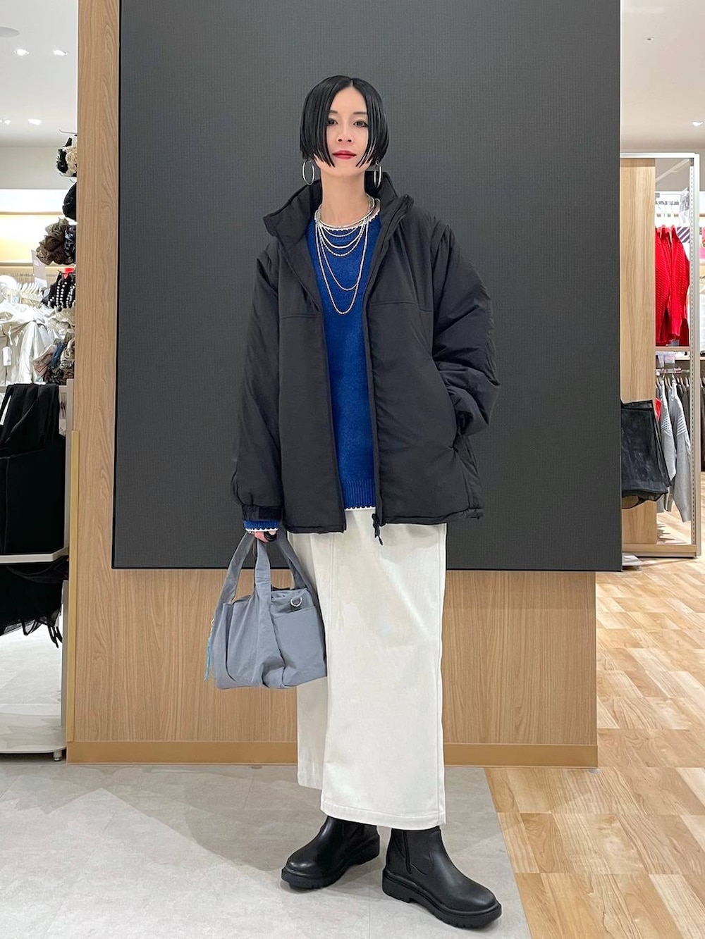グレー系のトートバッグ、ブラック系のブルゾン、グレー系のスカートを着用したレディースの冬コーディネートの6枚目の写真