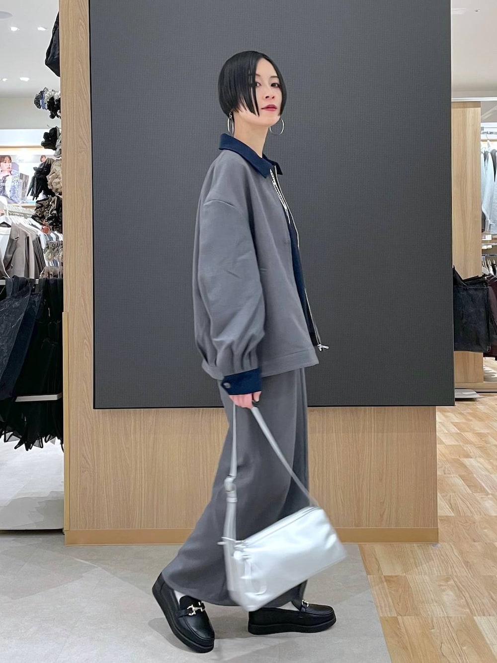 ブラック系のローファー、ブルー系のニット/セーター、シルバー系のショルダーバッグを着用したレディースの春コーディネートの2枚目の写真