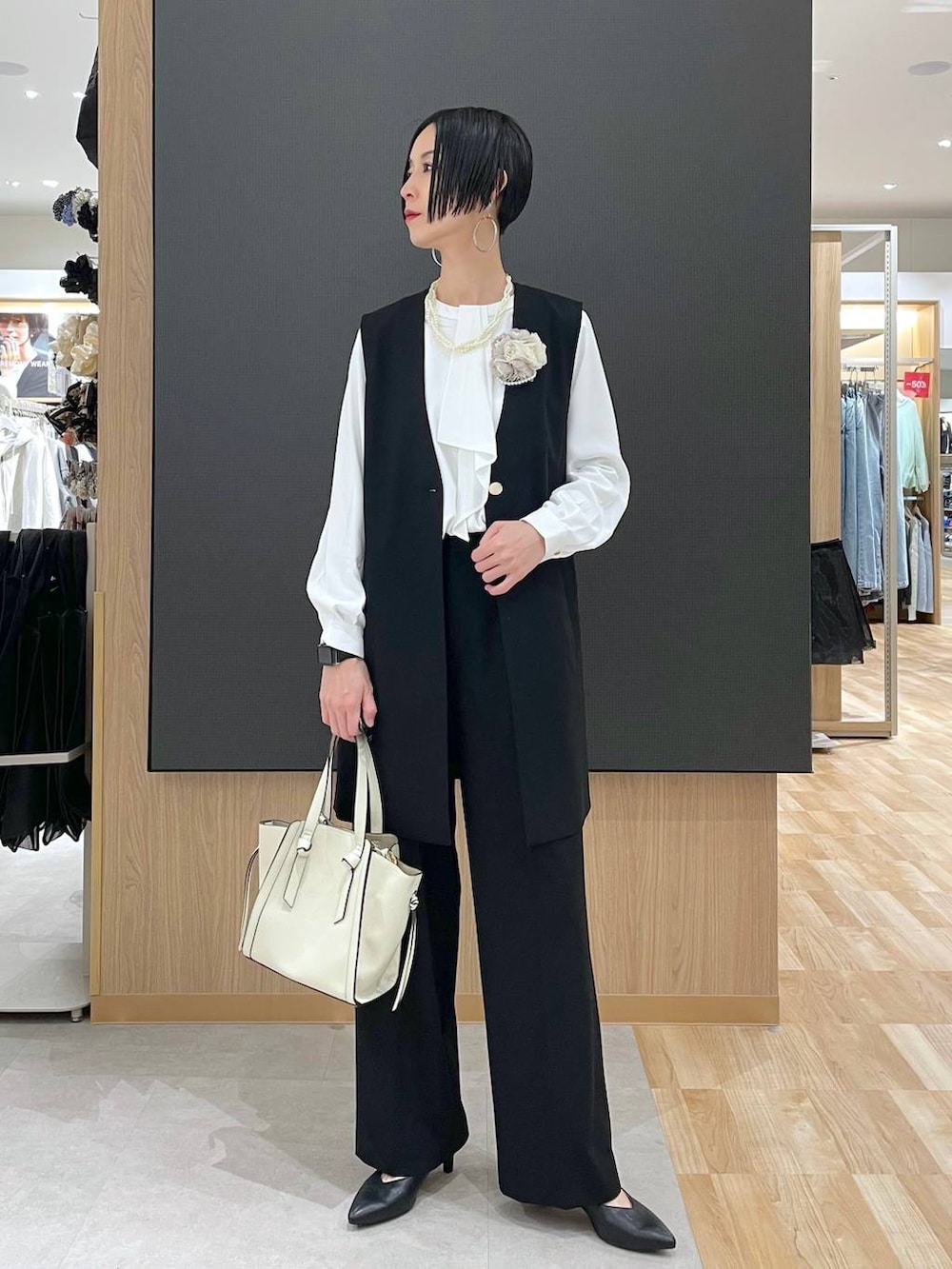 ホワイト系のショルダーバッグ、ブラック系のパンプス、ブラック系のスラックスを着用したレディースの冬コーディネートの6枚目の写真