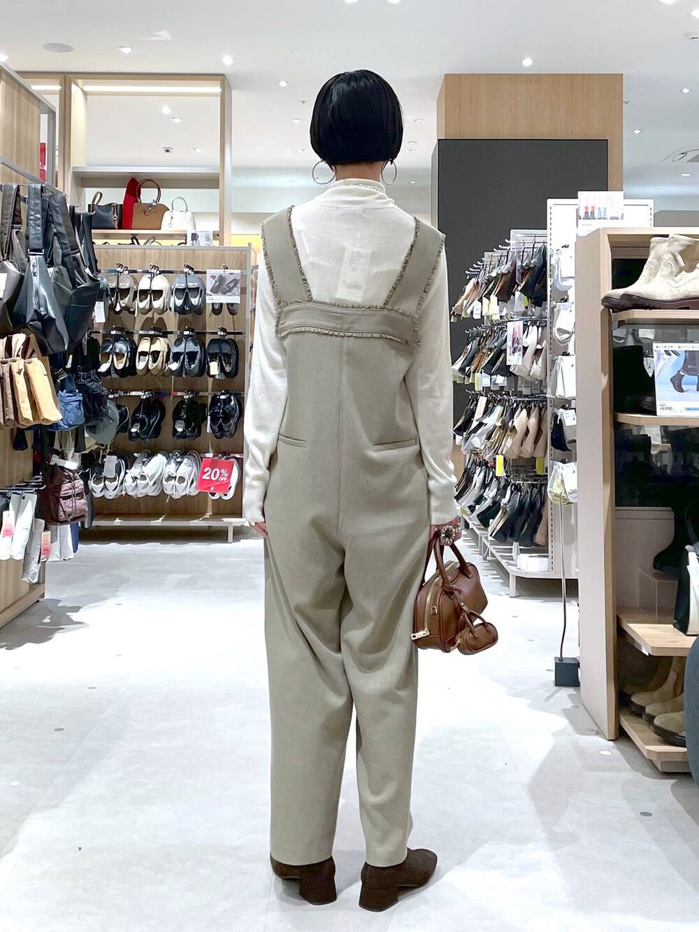 ブラウン系のハンドバッグ、ベージュ系のサロペット/オーバーオール、ホワイト系のニット/セーターを着用したレディースの秋コーディネートの10枚目の写真