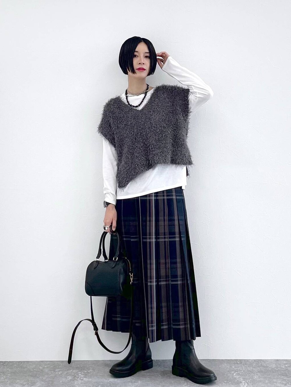 ブラック系のブーツ、グレー系のベスト、ブルー系のスカートを着用したレディースの秋コーディネートの2枚目の写真