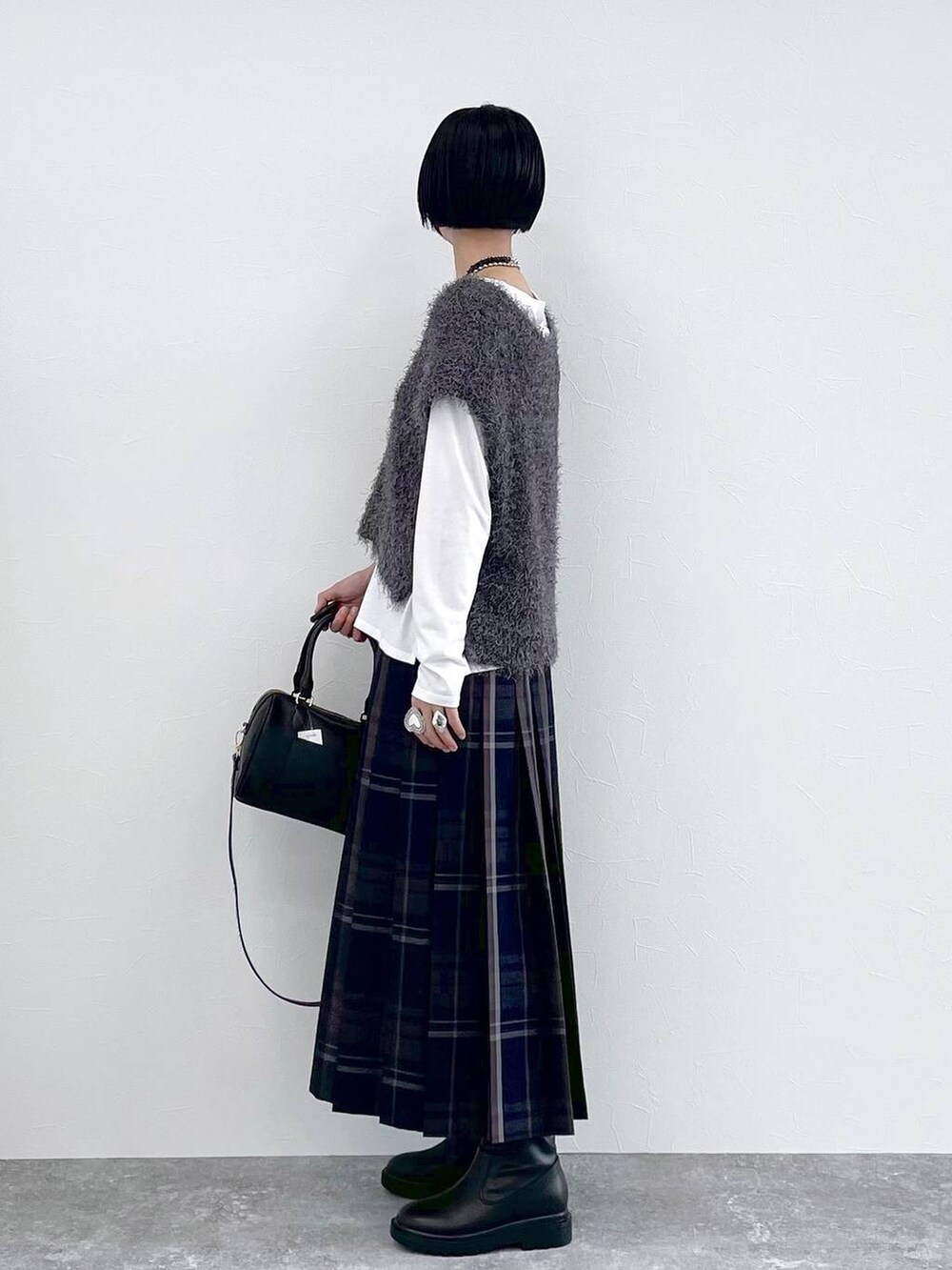 ブラック系のブーツ、グレー系のベスト、ブルー系のスカートを着用したレディースの秋コーディネートの5枚目の写真