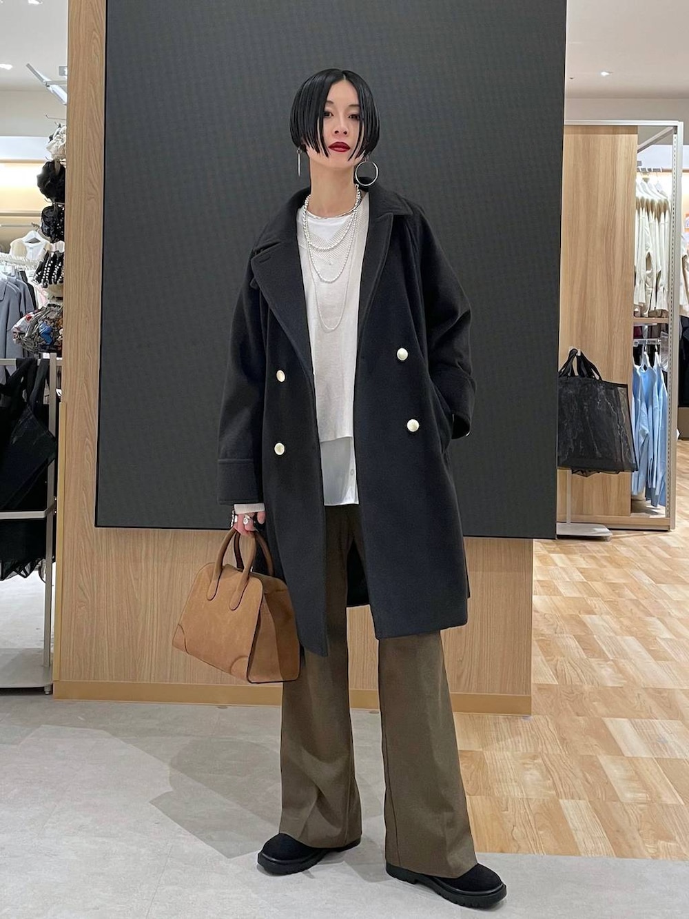 ブラック系のチェスターコート、ホワイト系のニット/セーター、ブラウン系のその他パンツを着用したレディースの冬コーディネートの5枚目の写真