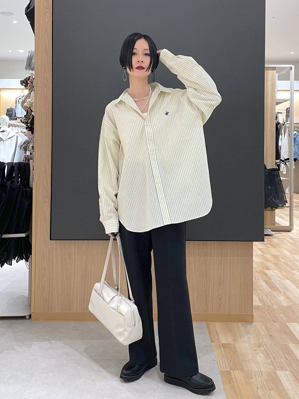 ブラック系のローファー、ブラック系のその他パンツ、ベージュ系のショルダーバッグを着用したレディースの春コーディネートの2枚目の写真