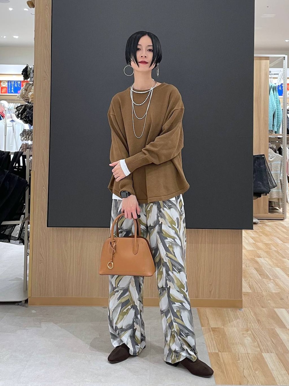 ブラウン系のショルダーバッグ、ブラウン系のニット/セーター、ブラウン系のブーツを着用したレディースの冬コーディネートの6枚目の写真