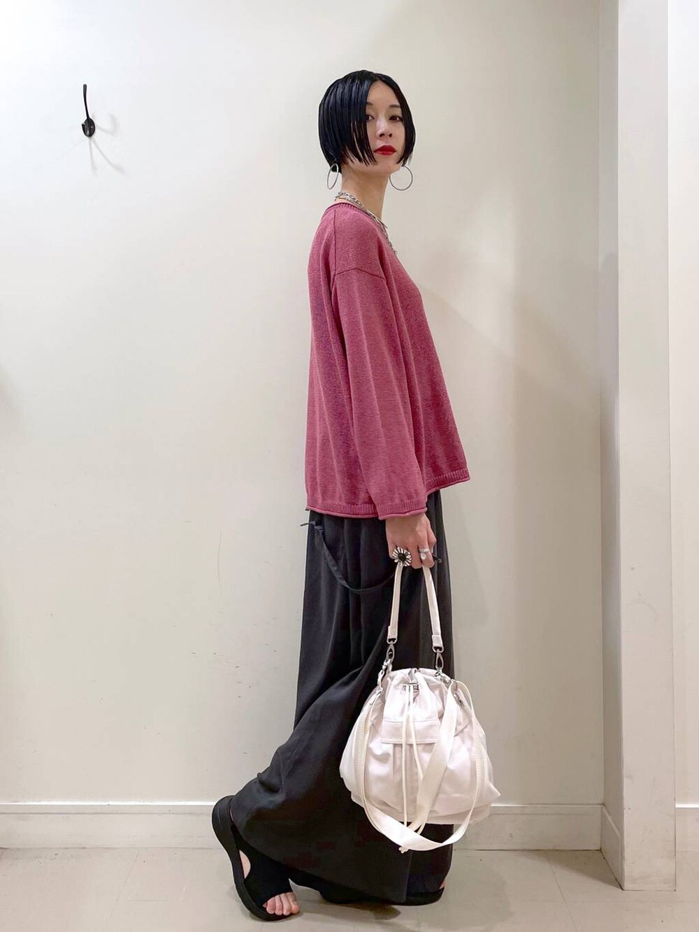 ホワイト系のショルダーバッグ、ブラック系のタンクトップ、ブラック系のサンダルを着用したレディースの秋コーディネートの3枚目の写真