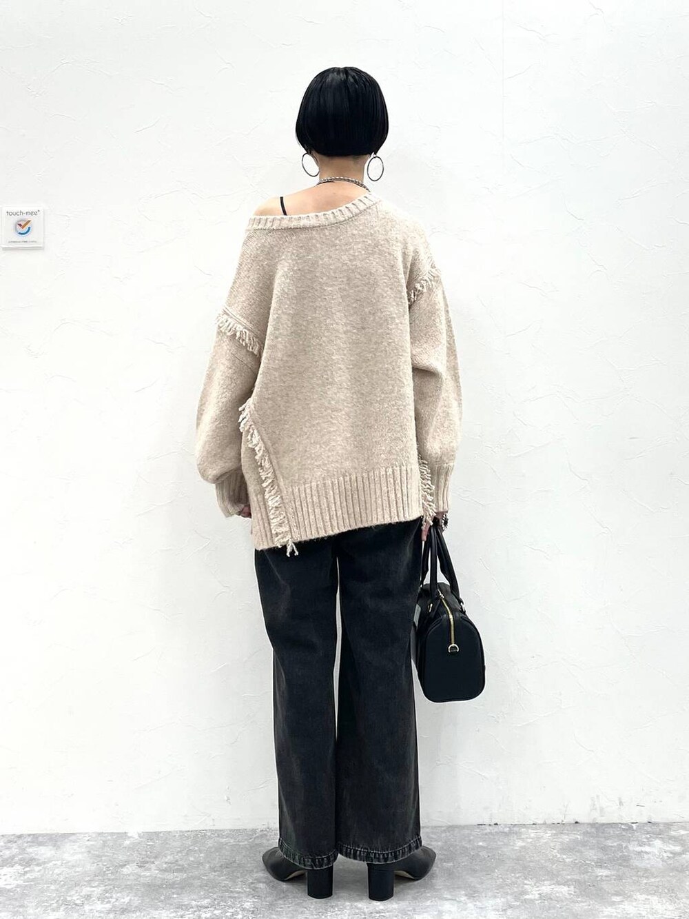 ブラック系のデニムパンツ、ブラック系のボストンバッグ、ブラック系のブーツを着用したレディースの冬コーディネートの4枚目の写真