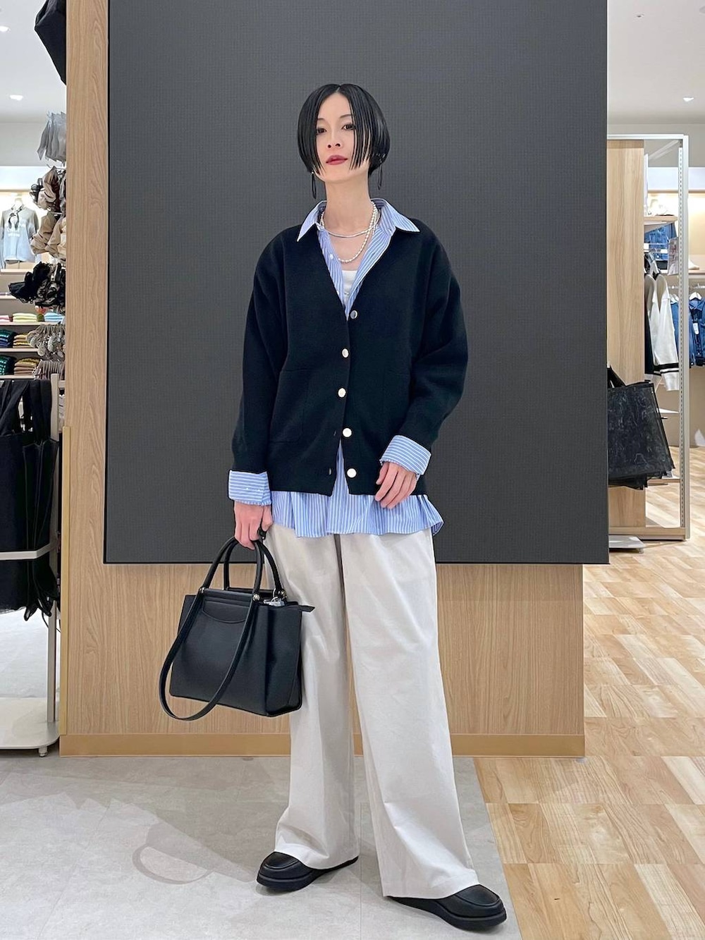 ブラック系のローファー、ブラック系のトートバッグ、ブルー系のシャツ/ブラウスを着用したレディースの春コーディネートの5枚目の写真
