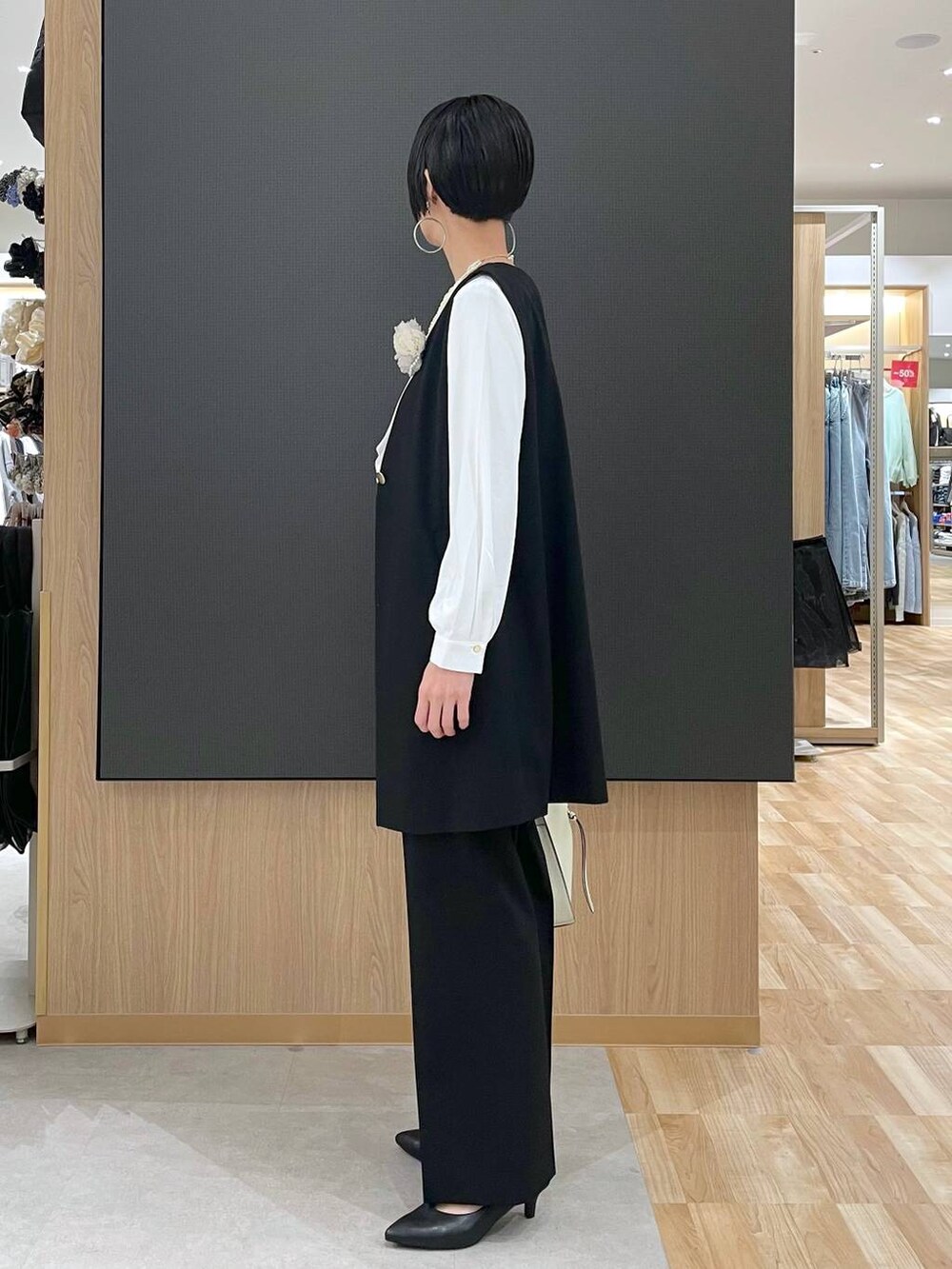 ホワイト系のショルダーバッグ、ブラック系のパンプス、ブラック系のスラックスを着用したレディースの冬コーディネートの4枚目の写真