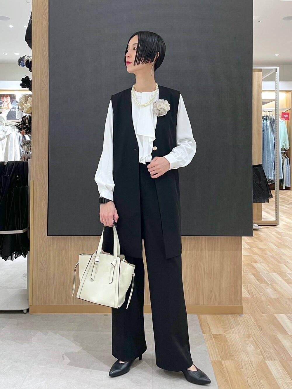 ホワイト系のショルダーバッグ、ブラック系のパンプス、ブラック系のスラックスを着用したレディースの冬コーディネートの5枚目の写真