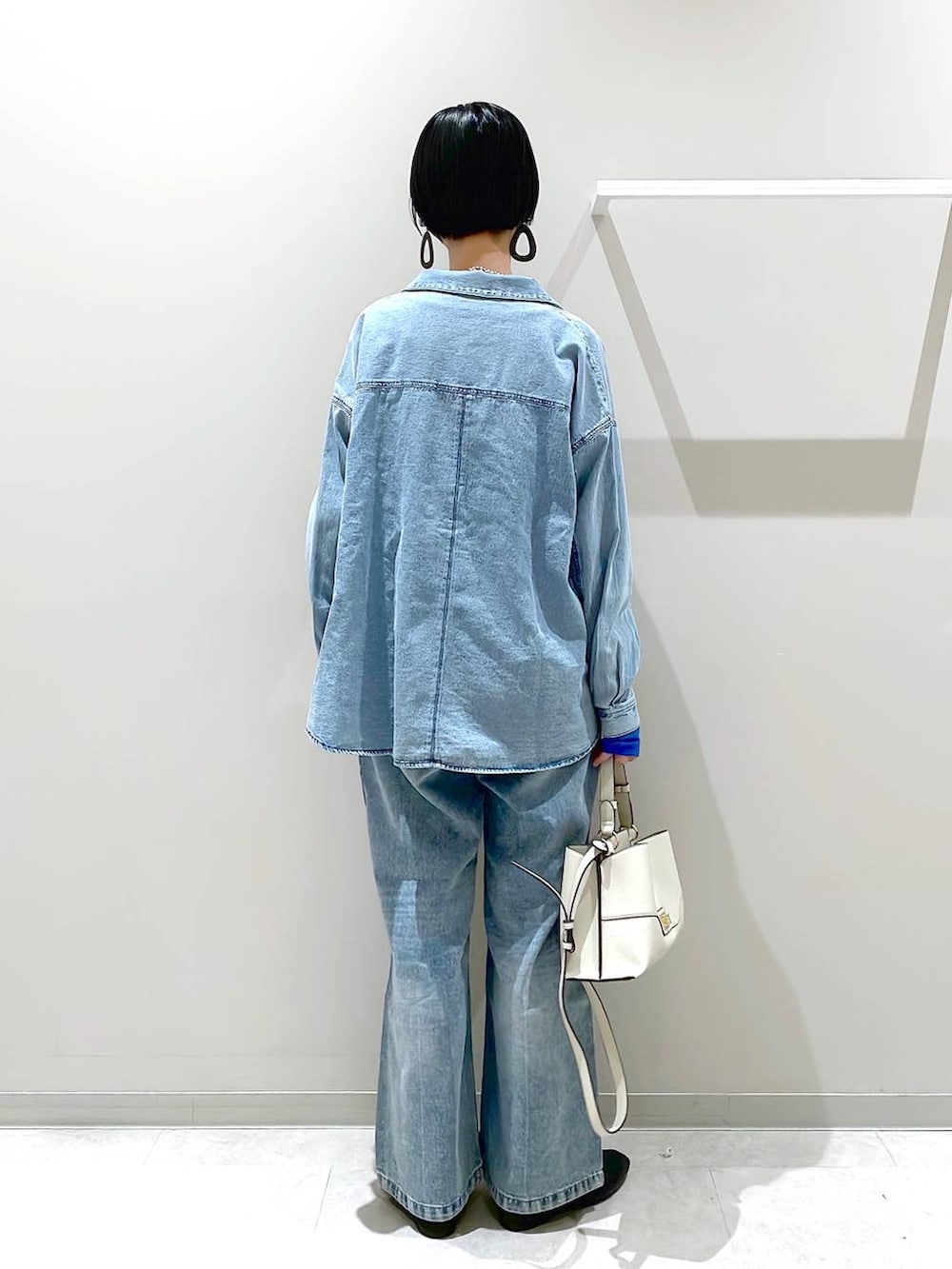 ブラック系のその他シューズ、ブルー系のデニムパンツ、ベージュ系のショルダーバッグを着用したレディースの春コーディネートの3枚目の写真