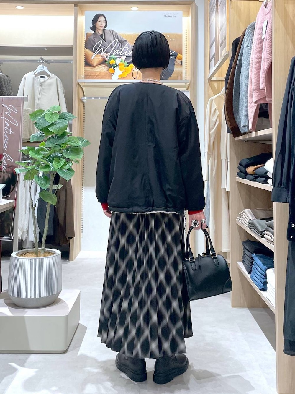 ホワイト系のブルゾン、ブラック系のブーツ、レッド系のニット/セーターを着用したレディースの秋コーディネートの3枚目の写真