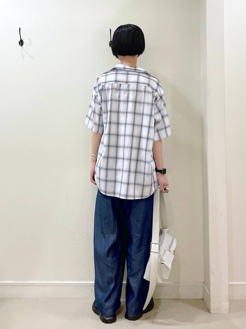 ブラック系のスニーカー、ホワイト系のショルダーバッグ、ホワイト系のシャツ/ブラウスを着用したレディースの夏コーディネートの3枚目の写真