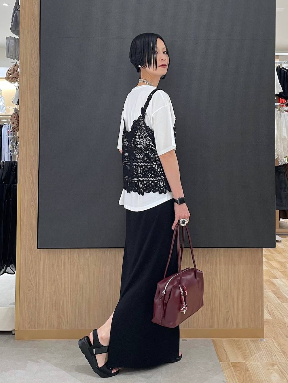 ブラック系のスカート、レッド系のボストンバッグ、ホワイト系のTシャツ/カットソーを着用したレディースの夏コーディネートの2枚目の写真