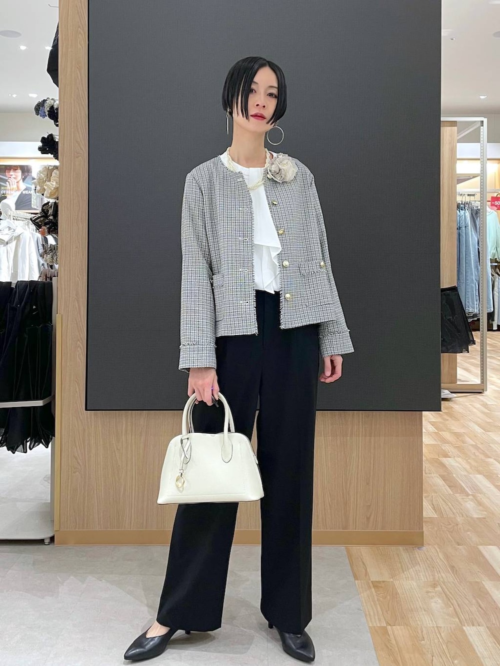 ホワイト系のショルダーバッグ、ブラック系のパンプス、ブラック系のスラックスを着用したレディースの冬コーディネートの6枚目の写真