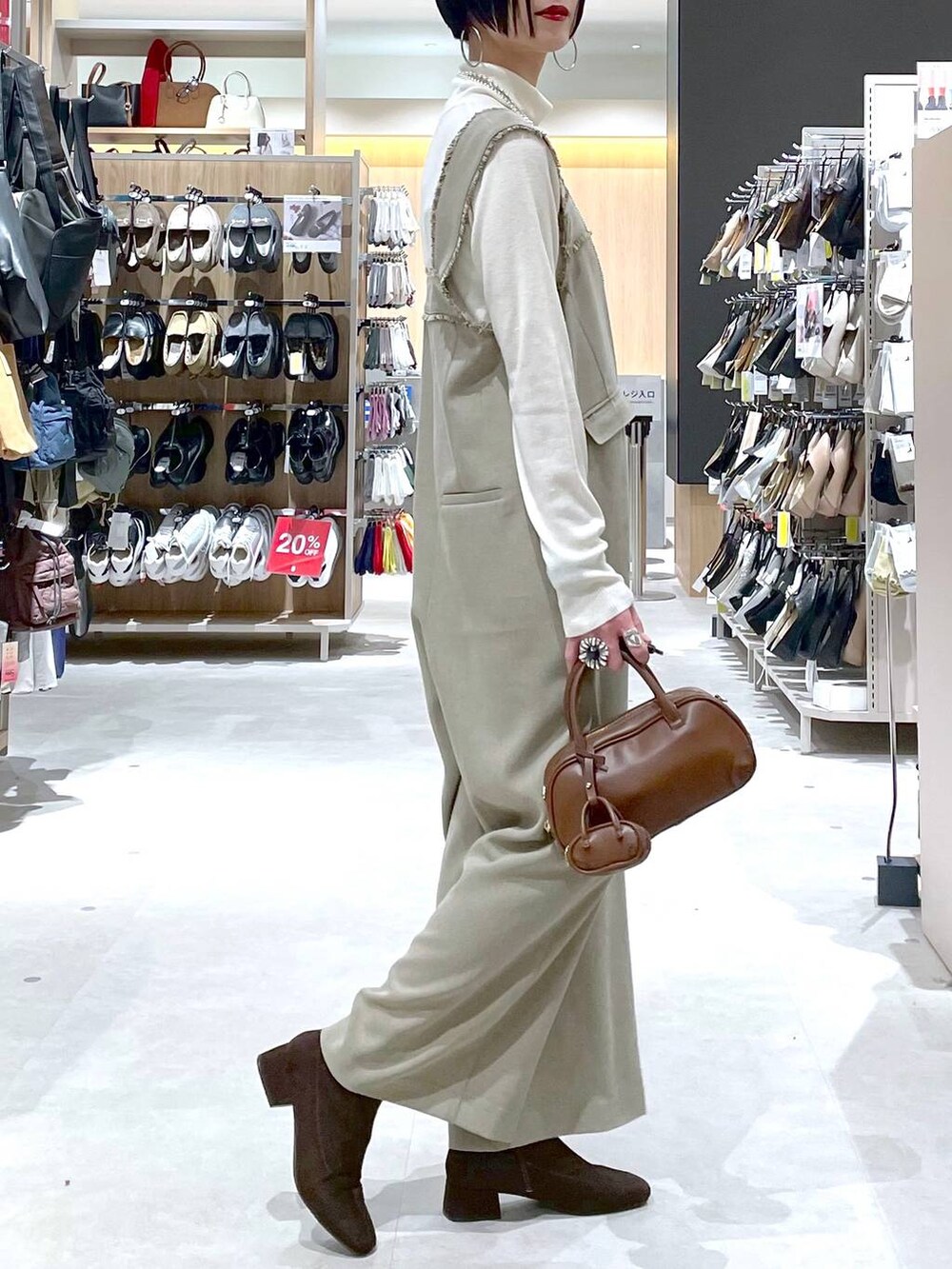ブラウン系のハンドバッグ、ベージュ系のサロペット/オーバーオール、ホワイト系のニット/セーターを着用したレディースの秋コーディネートの9枚目の写真
