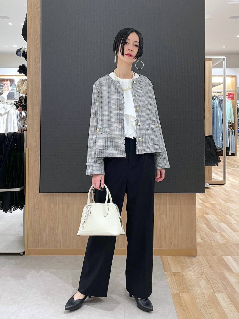 ホワイト系のショルダーバッグ、ブラック系のパンプス、ブラック系のスラックスを着用したレディースの冬コーディネートの2枚目の写真