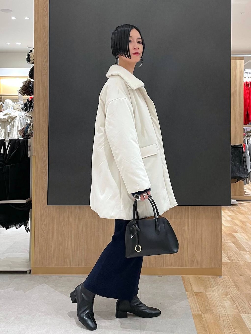 ブラック系のショルダーバッグ、ブルー系のワンピース、ブラック系のブーツを着用したレディースの冬コーディネートの3枚目の写真