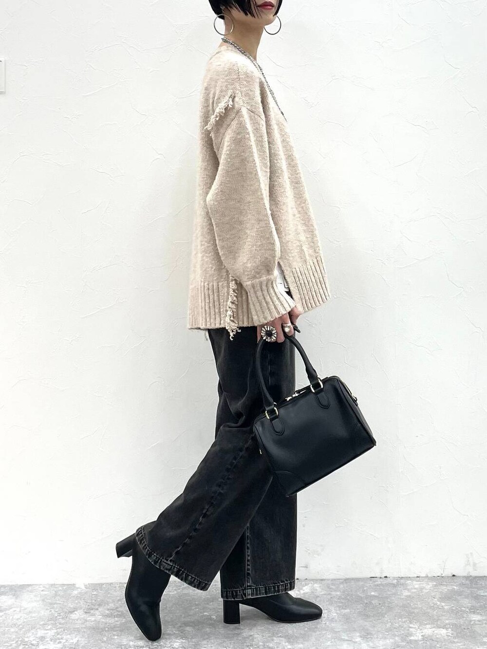 ブラック系のデニムパンツ、ブラック系のボストンバッグ、ブラック系のブーツを着用したレディースの冬コーディネートの3枚目の写真