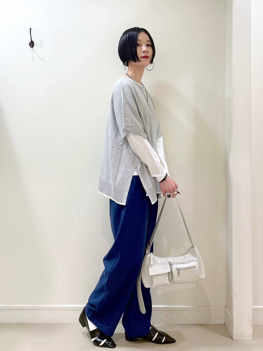 ホワイト系のショルダーバッグ、ホワイト系のTシャツ/カットソー、グレー系のニット/セーターを着用したレディースの春コーディネートの3枚目の写真