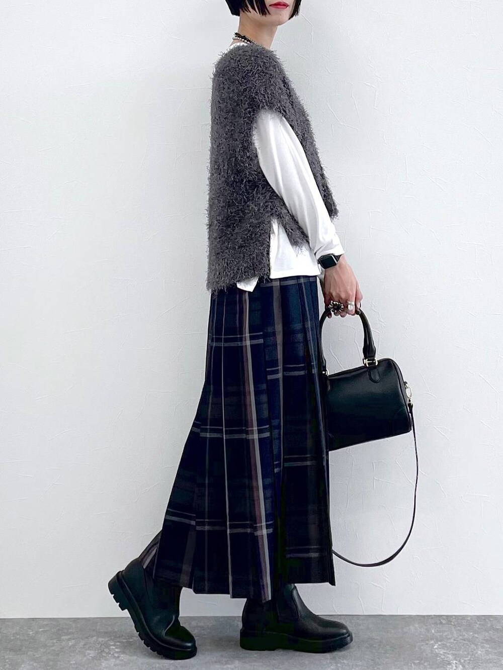 ブラック系のブーツ、グレー系のベスト、ブルー系のスカートを着用したレディースの秋コーディネートの3枚目の写真