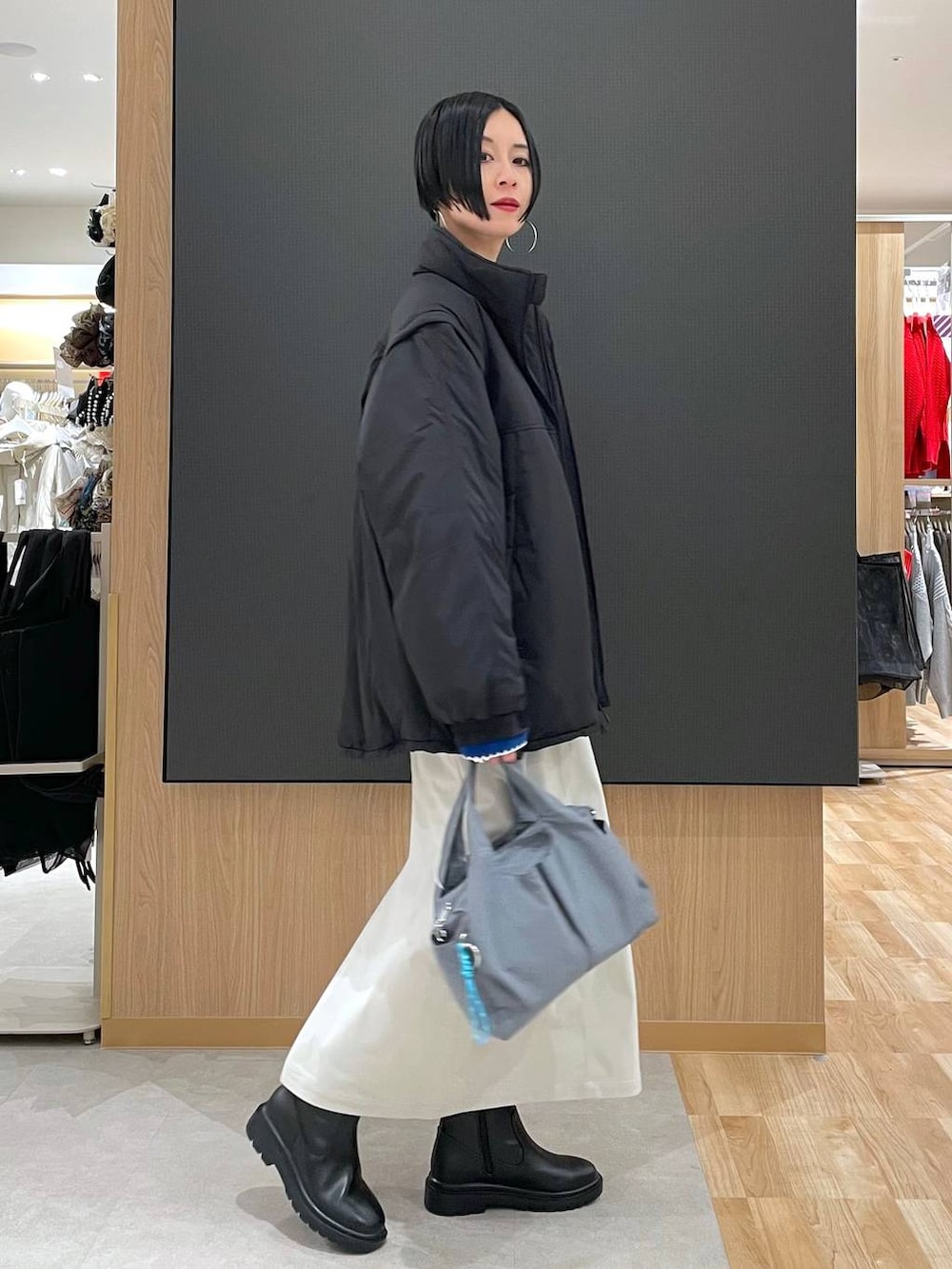 グレー系のトートバッグ、ブラック系のブルゾン、グレー系のスカートを着用したレディースの冬コーディネートの3枚目の写真