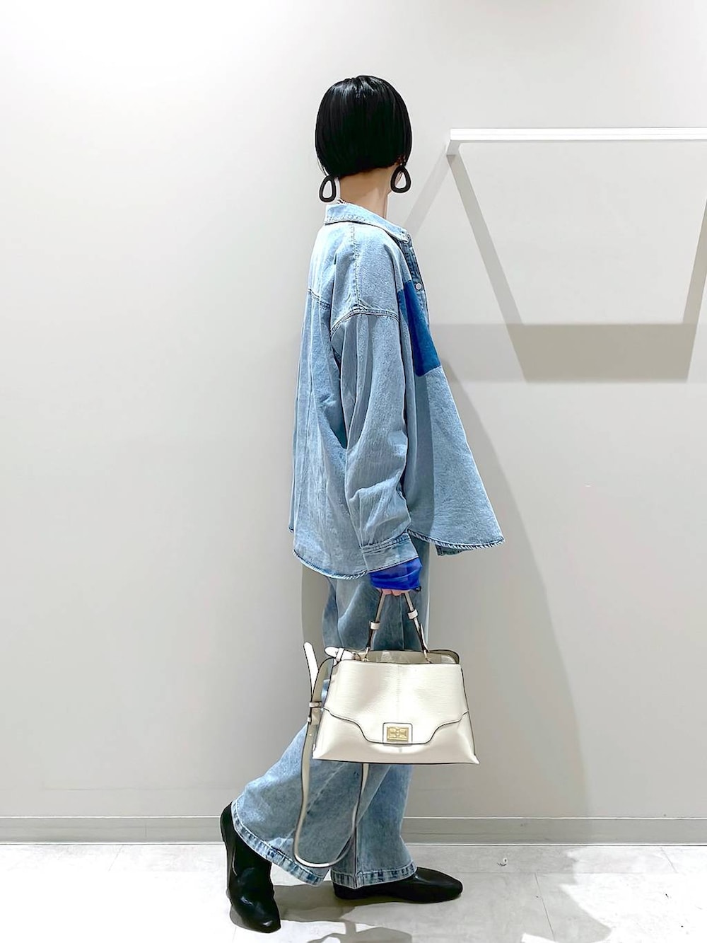 ブラック系のその他シューズ、ブルー系のデニムパンツ、ベージュ系のショルダーバッグを着用したレディースの春コーディネートの2枚目の写真