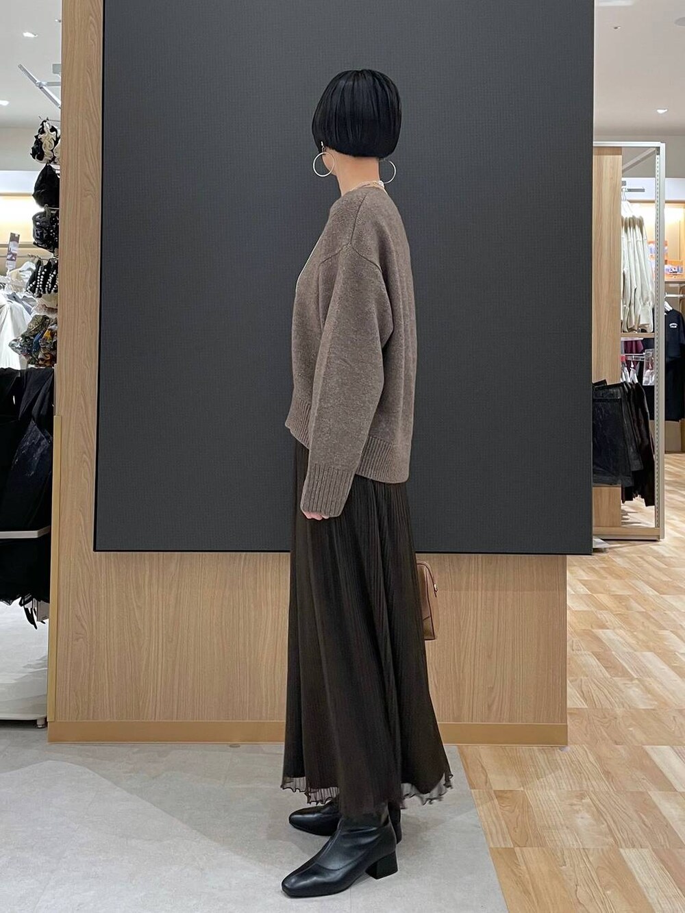 ベージュ系のボストンバッグ、ブラック系のブーツ、シルバー系のネックレスを着用したレディースの冬コーディネートの5枚目の写真