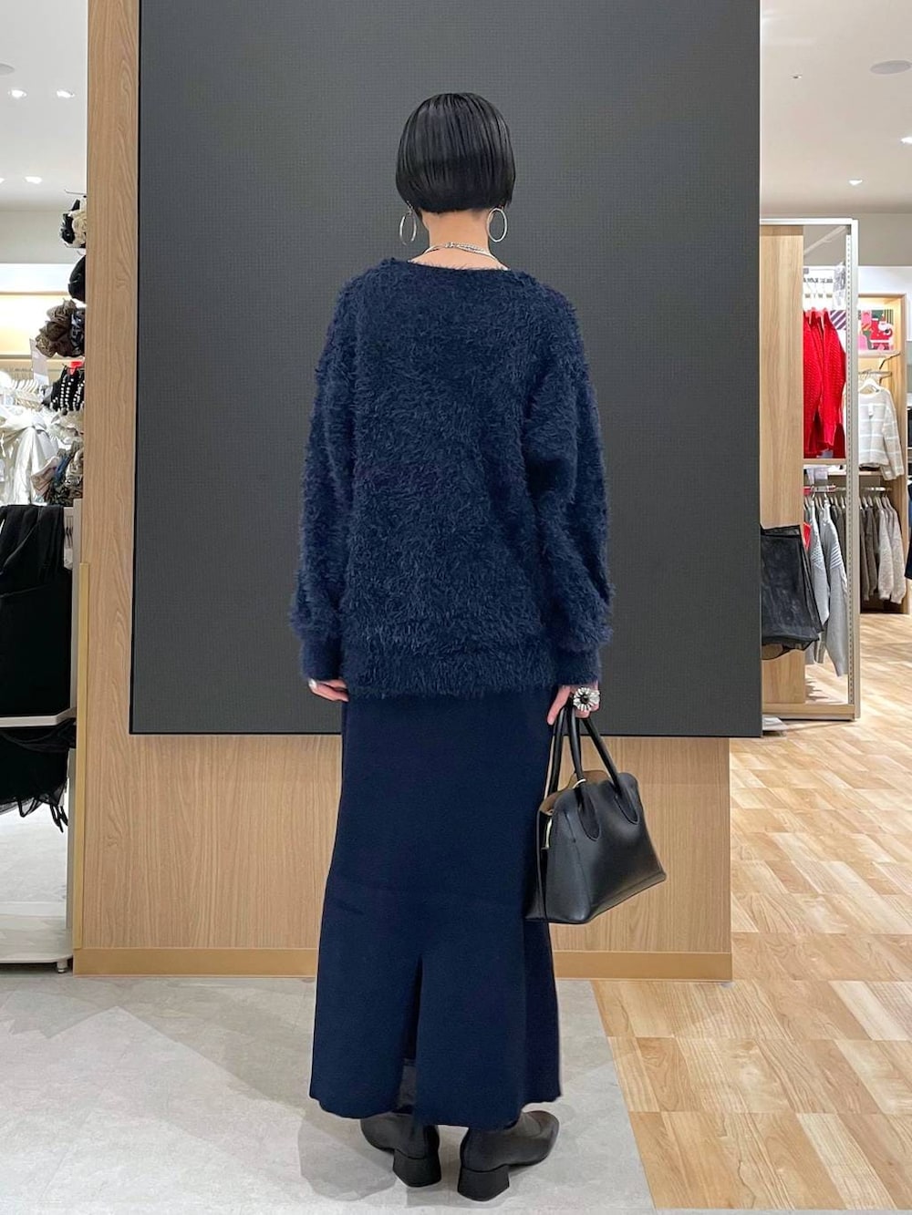 ブラック系のショルダーバッグ、ブルー系のワンピース、ブラック系のブーツを着用したレディースの冬コーディネートの9枚目の写真