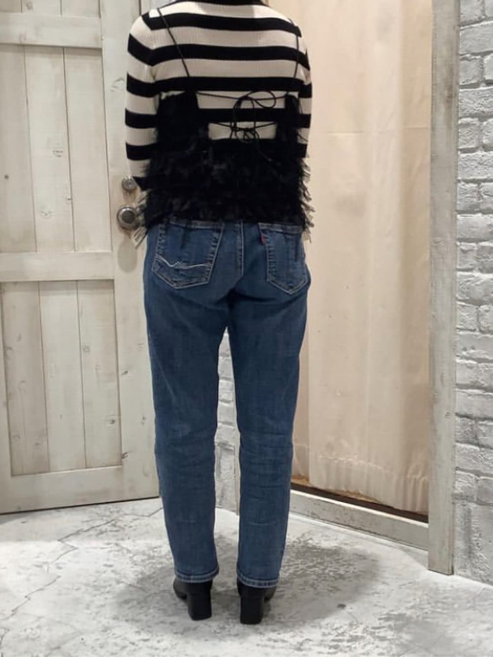 ブルー系のデニムパンツ、ブラック系のキャミソール、ホワイト系のニット/セーターを着用したレディースの冬コーディネートの2枚目の写真