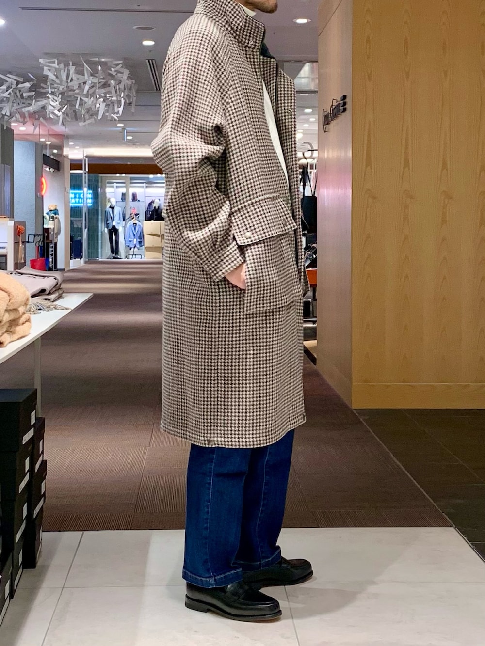 ホワイト系のニット/セーター、ベージュ系のステンカラーコート、ブルー系のデニムパンツを着用したメンズの冬コーディネートの2枚目の写真