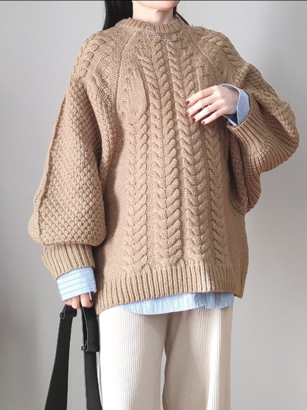 ベージュ系のニット/セーター、ブラック系のショルダーバッグ、ブラック系のレインシューズを着用したレディースの冬コーディネートの2枚目の写真