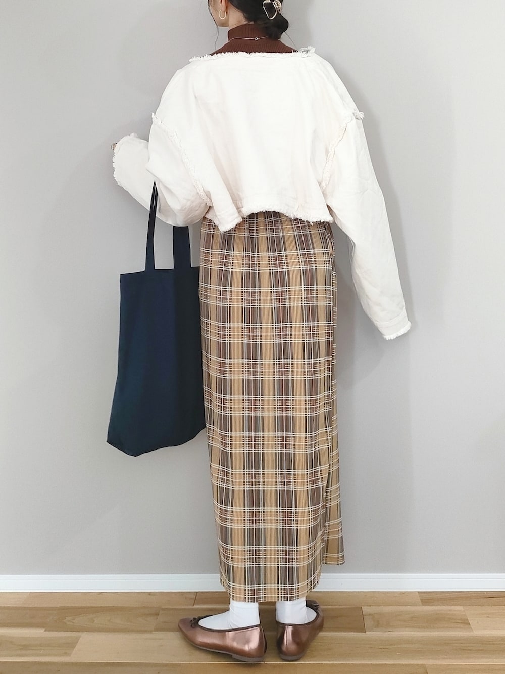 ホワイト系のデニムジャケット、イエロー系のスカート、ブルー系のトートバッグを着用したレディースの冬コーディネートの3枚目の写真