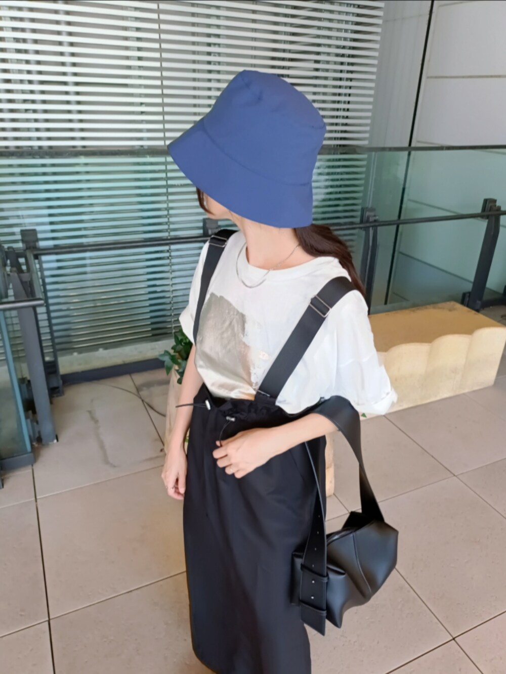 ブラック系のジャンパースカート、ホワイト系のTシャツ/カットソー、ブラック系のショルダーバッグを着用したレディースの夏コーディネートの3枚目の写真