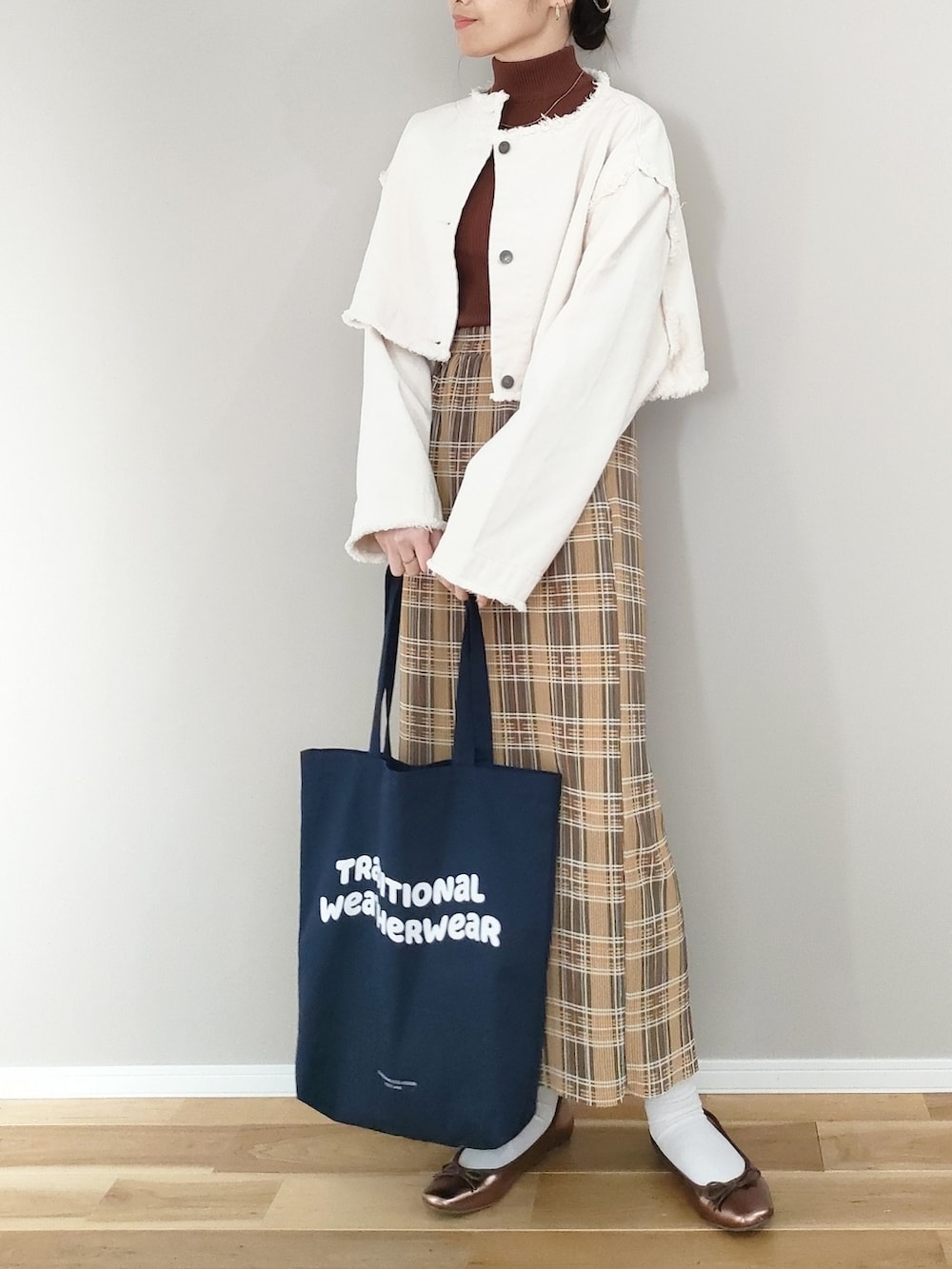 ホワイト系のデニムジャケット、イエロー系のスカート、ブルー系のトートバッグを着用したレディースの冬コーディネートの4枚目の写真