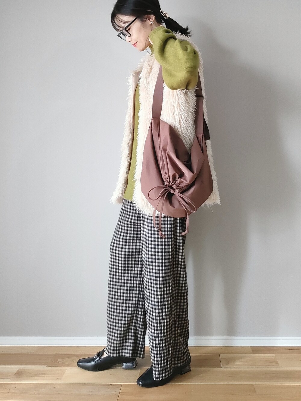 グリーン系のニット/セーター、ホワイト系のベスト、ブラウン系のショルダーバッグを着用したレディースの秋コーディネートの3枚目の写真