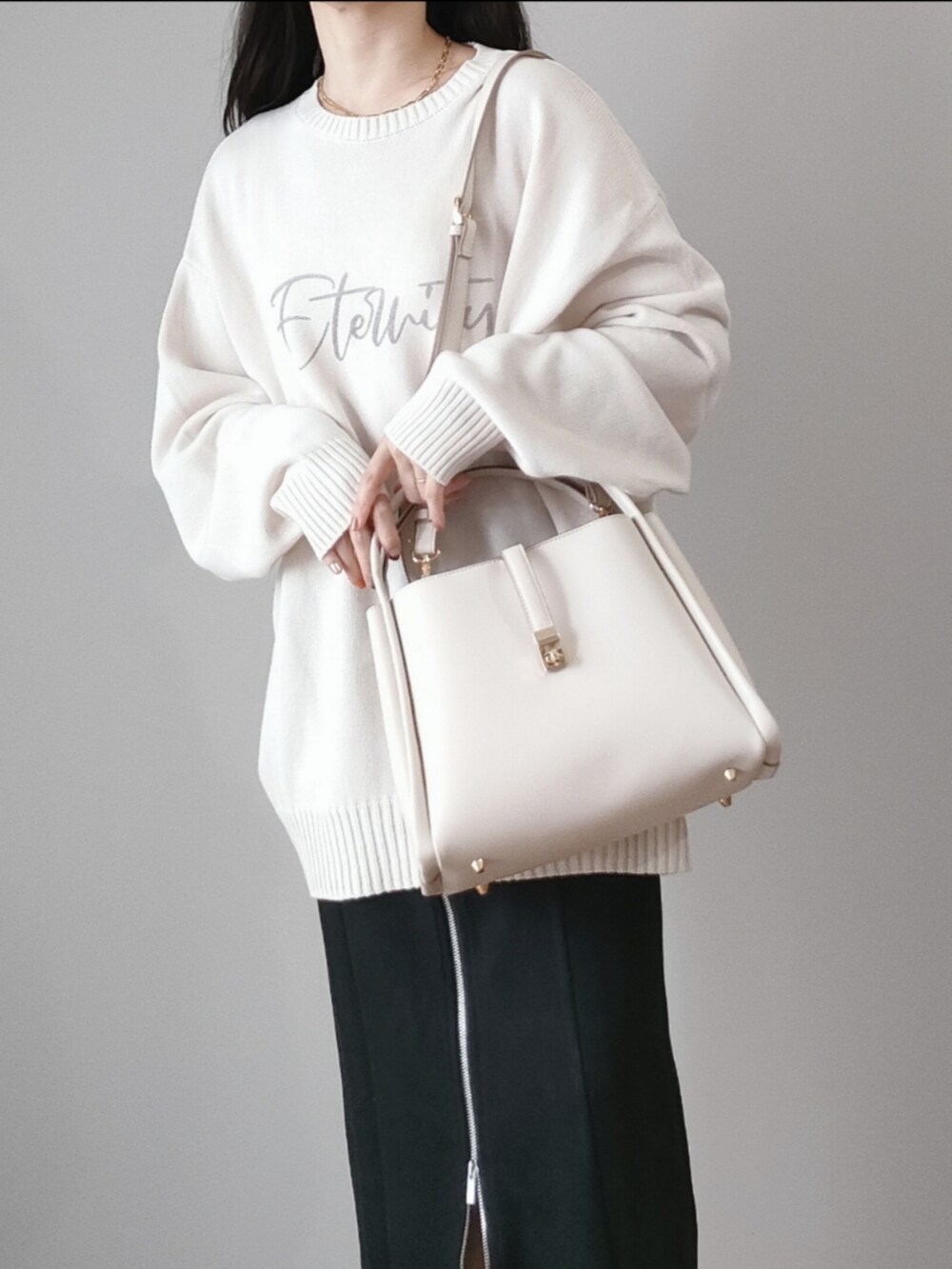 ホワイト系のトートバッグ、ブラック系のスカート、ホワイト系のニット/セーターを着用したレディースの秋コーディネートの2枚目の写真