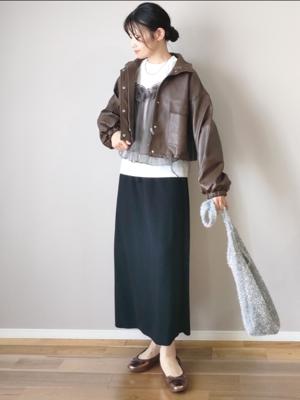 ブラウン系のブルゾン、ホワイト系のTシャツ/カットソー、ブラック系のスカートを着用したレディースの秋コーディネートの2枚目の写真