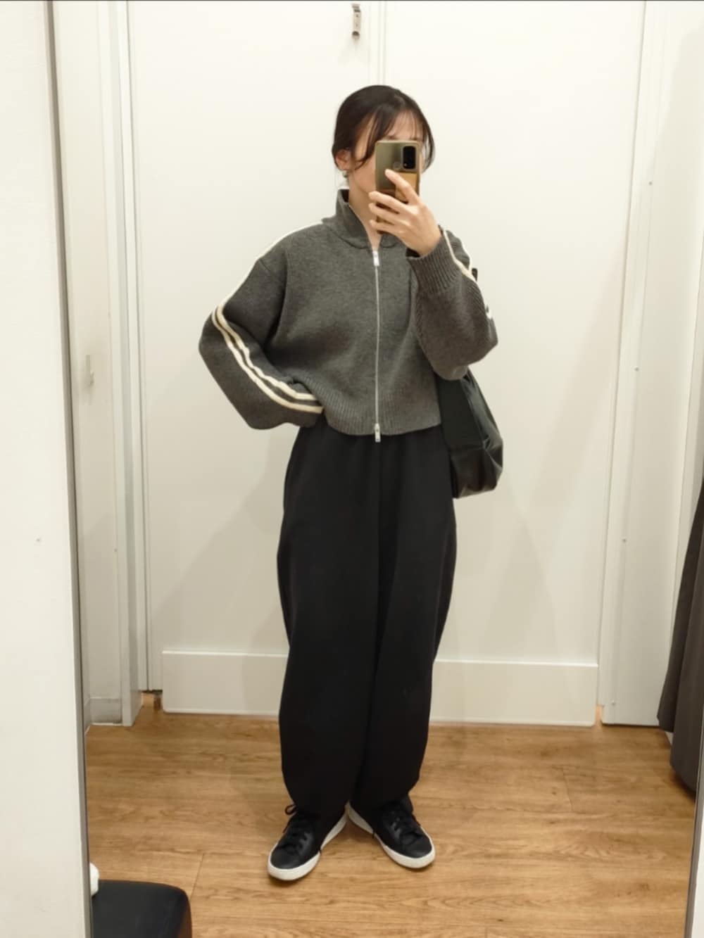 グレー系のニット/セーター、ブラック系のスウェットパンツ、ブラック系のショルダーバッグを着用したレディースの冬コーディネートの2枚目の写真
