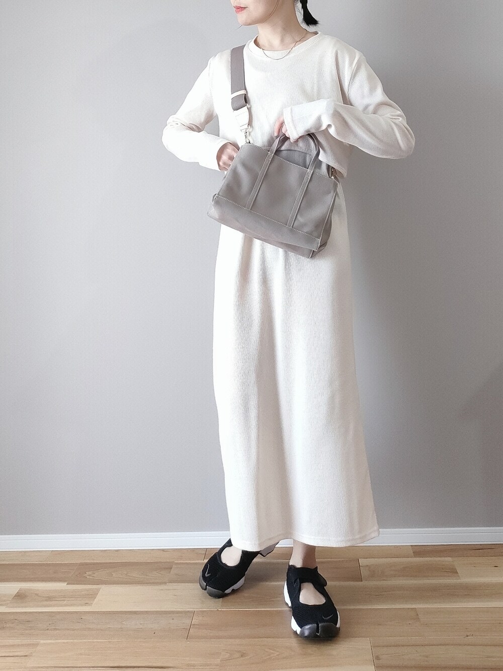 ホワイト系のワンピース、グレー系のハンドバッグ、ブラック系のスニーカーを着用したレディースの春コーディネートの2枚目の写真