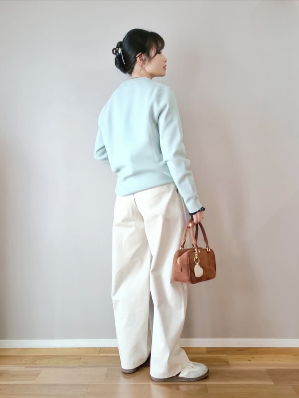 グリーン系のトップス、ホワイト系のチノパンツ、ブラウン系のボストンバッグを着用したレディースの春コーディネートの3枚目の写真