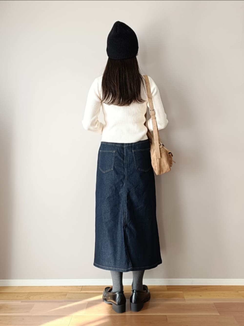 ブルー系のデニムスカート、ホワイト系のニット/セーター、ブラック系のローファーを着用したレディースの冬コーディネートの4枚目の写真