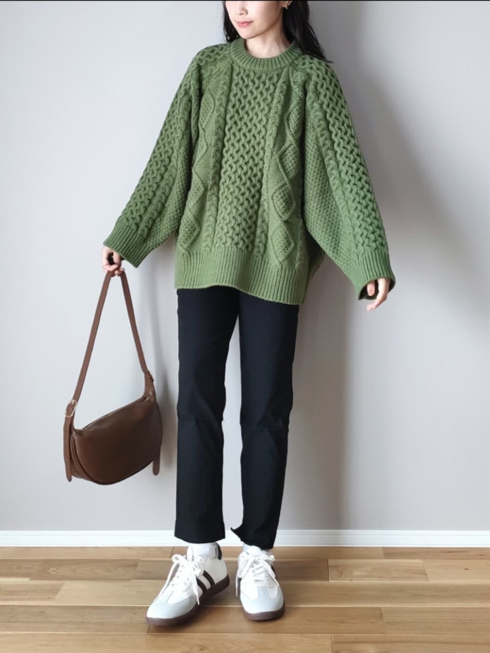 グリーン系のニット/セーター、ブラウン系のショルダーバッグ、グレー系のスニーカーを着用したレディースの秋コーディネートの3枚目の写真