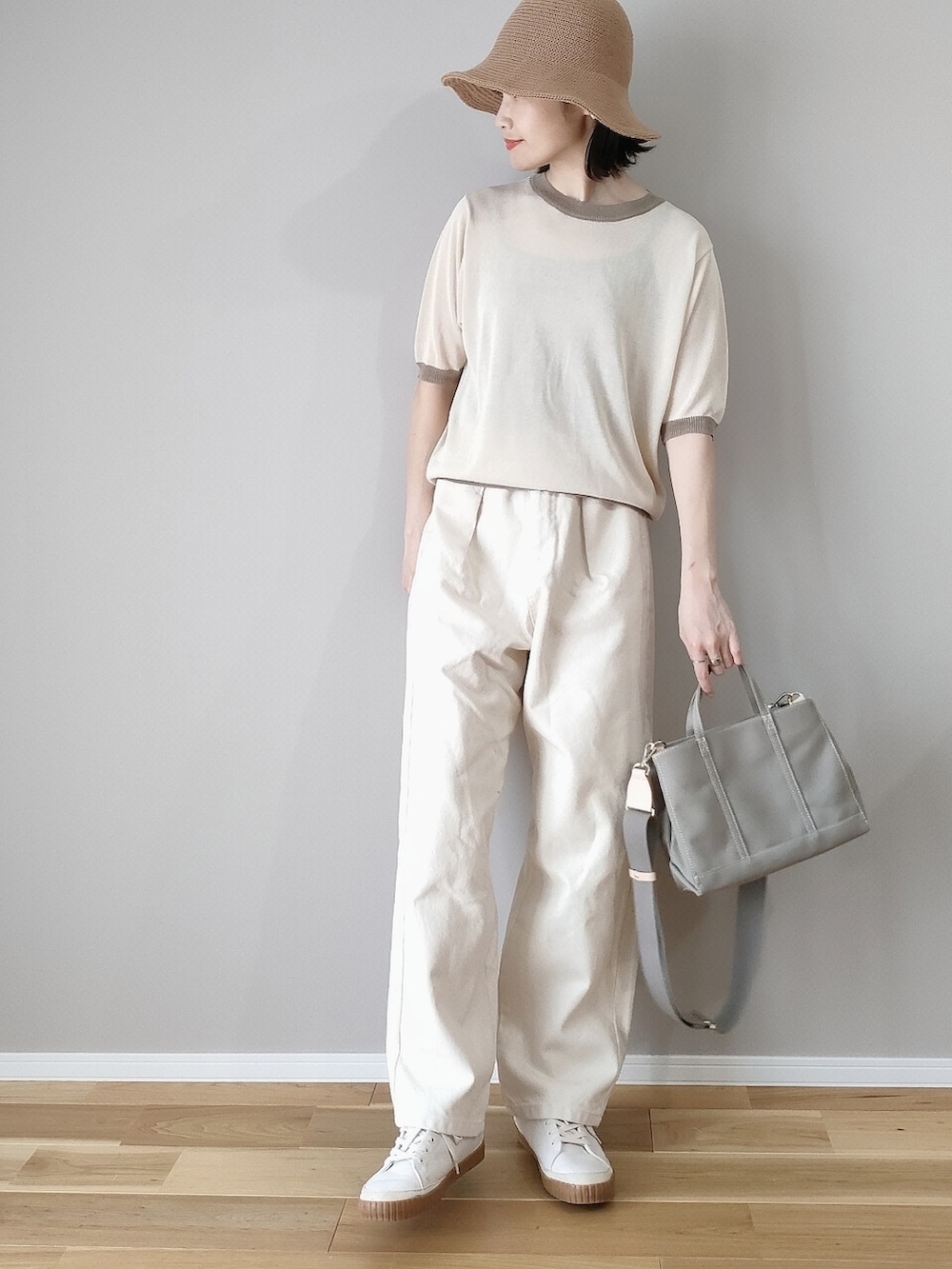 ベージュ系のニット/セーター、グレー系のハンドバッグ、ホワイト系のデニムパンツを着用したレディースの春コーディネートの2枚目の写真