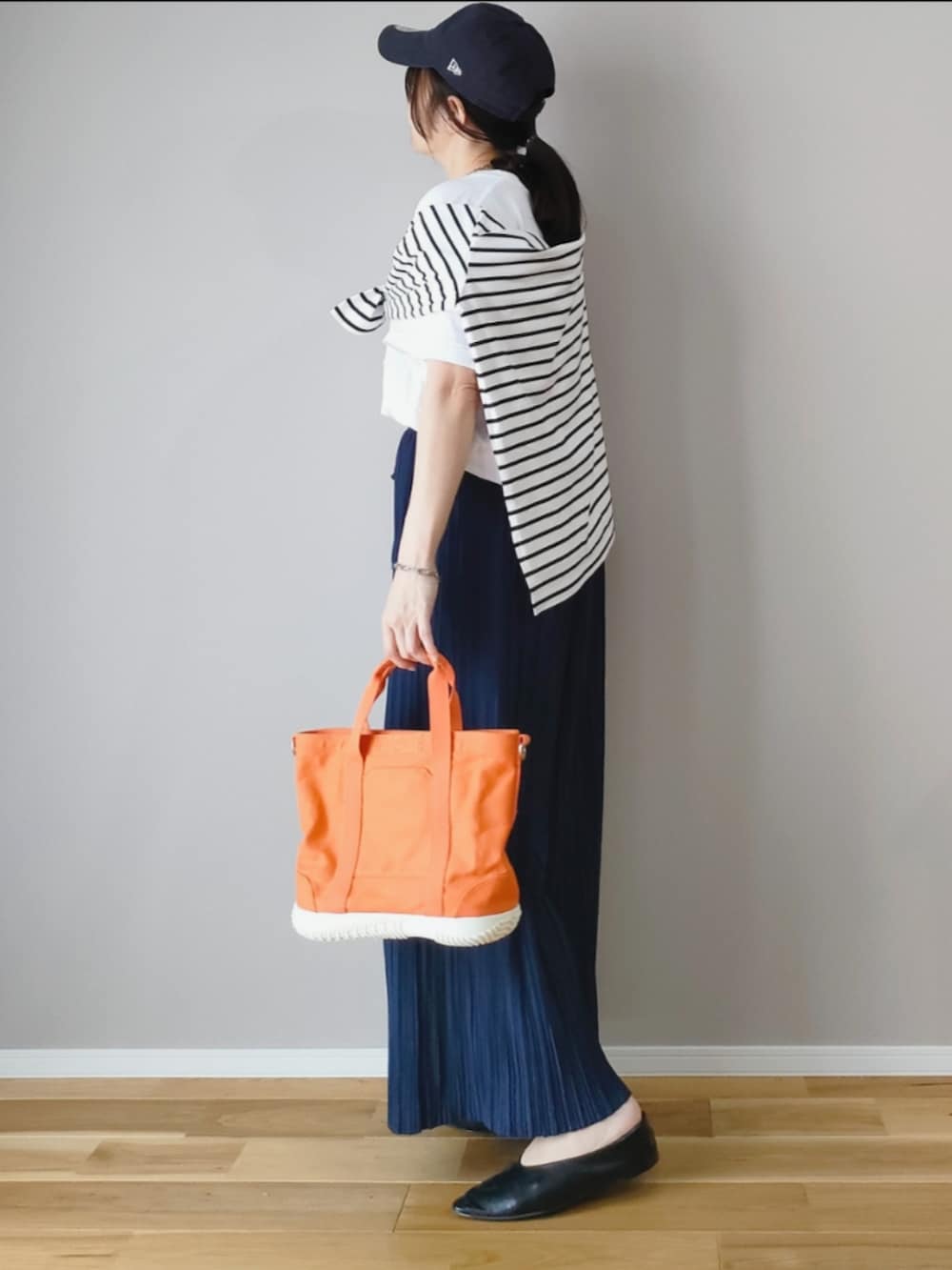 オレンジ系のトートバッグ、ブルー系のその他パンツ、ホワイト系のTシャツ/カットソーを着用したレディースの春コーディネートの4枚目の写真
