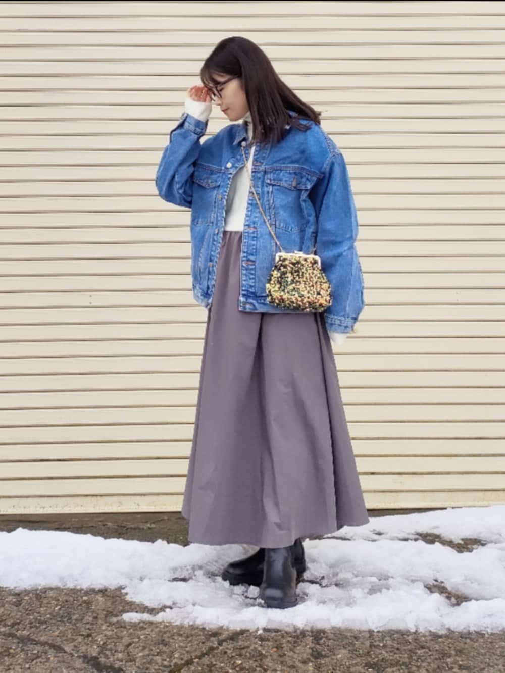ブルー系のデニムジャケット、ホワイト系のワンピース、ゴールド系のハンドバッグを着用したレディースの冬コーディネートの4枚目の写真
